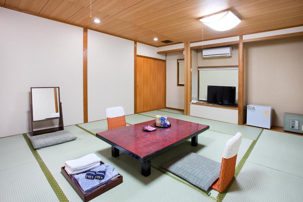 une pièce avec une table, des chaises et une télévision dans l'établissement Tsuruya Ryokan, à Kotohira
