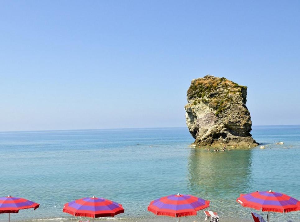 - un groupe de parasols sur une plage avec un rocher dans l'établissement Hotel Rodian, à Acquappesa