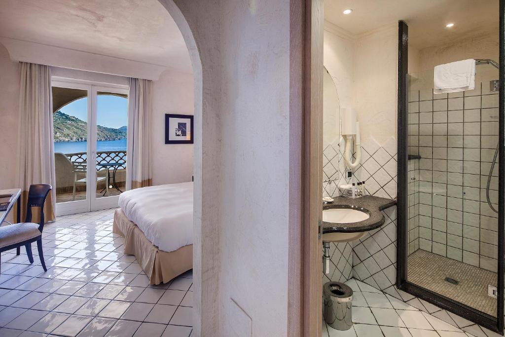 une chambre d'hôtel avec un lit et une salle de bain dans l'établissement Therasia Resort Sea and SPA - The Leading Hotels of the World, à Vulcano