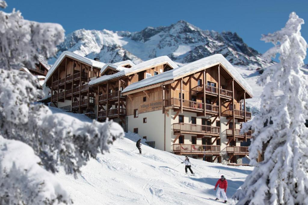 3 personnes skier sur une piste enneigée en face d'un lodge de ski dans l'établissement Residence Montana Plein Sud, à Val Thorens