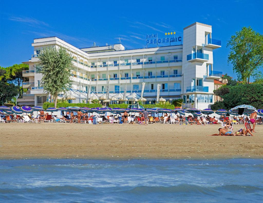 un groupe de personnes sur la plage devant un hôtel dans l'établissement Hotel Panoramic, à Caorle