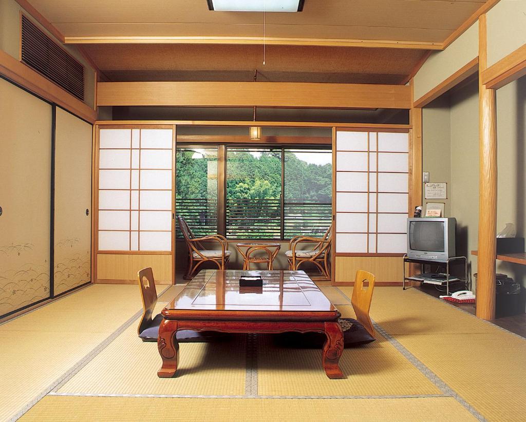 une pièce avec une table, des chaises et une télévision dans l'établissement Ryujin Onsen Marui Ryokan, à Tanabe