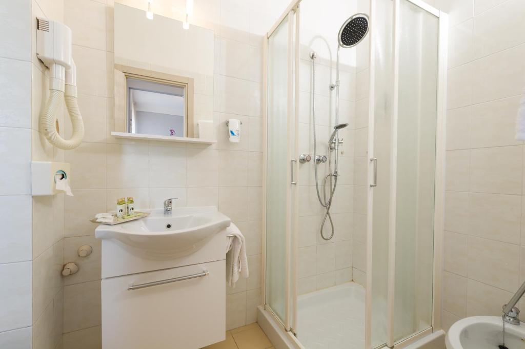 une salle de bain blanche avec une douche et un lavabo dans l'établissement Albergo Battelli Only Adults, à Marina di Pietrasanta