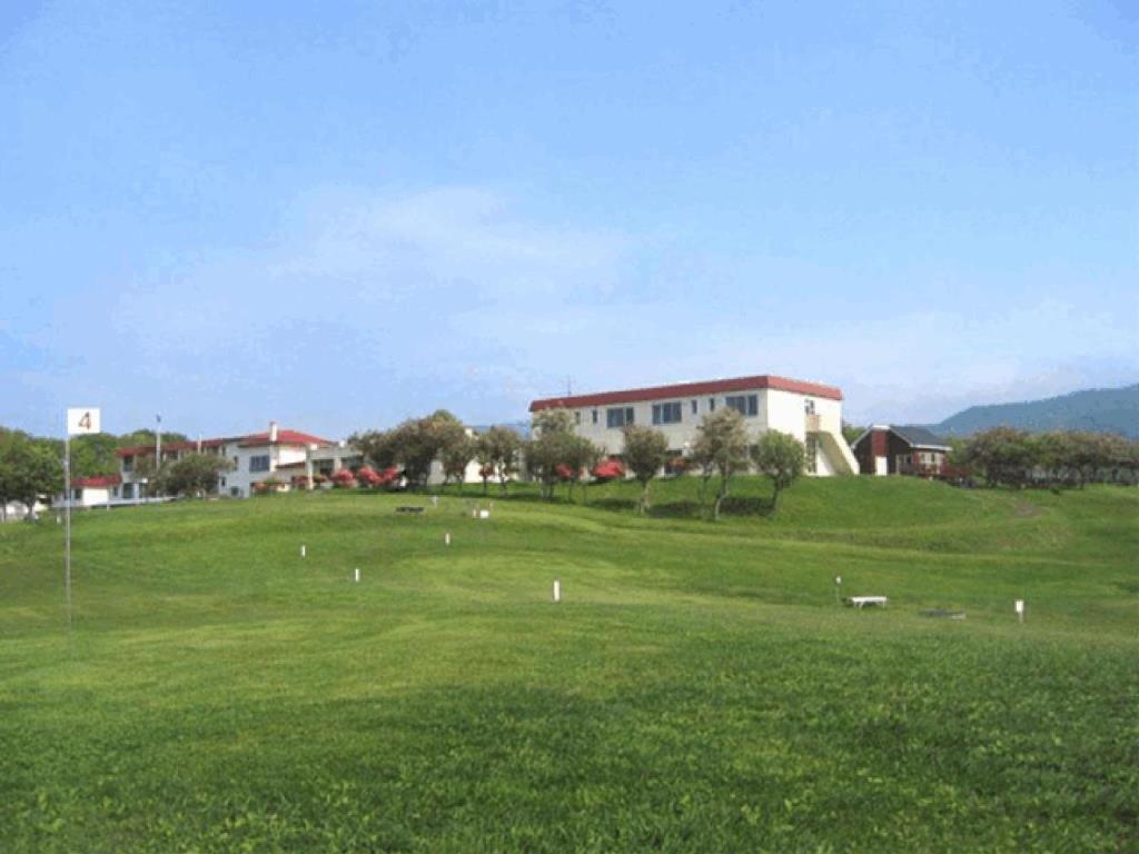 un champ d'herbe verte avec un bâtiment en arrière-plan dans l'établissement Hotel Izumi, à Shiraoi 33 autres photos