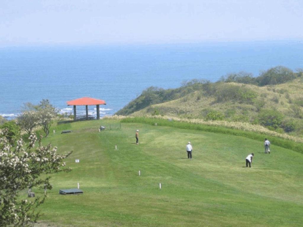un groupe de personnes jouant au golf sur une colline près de l'océan dans l'établissement Hotel Izumi, à Shiraoi