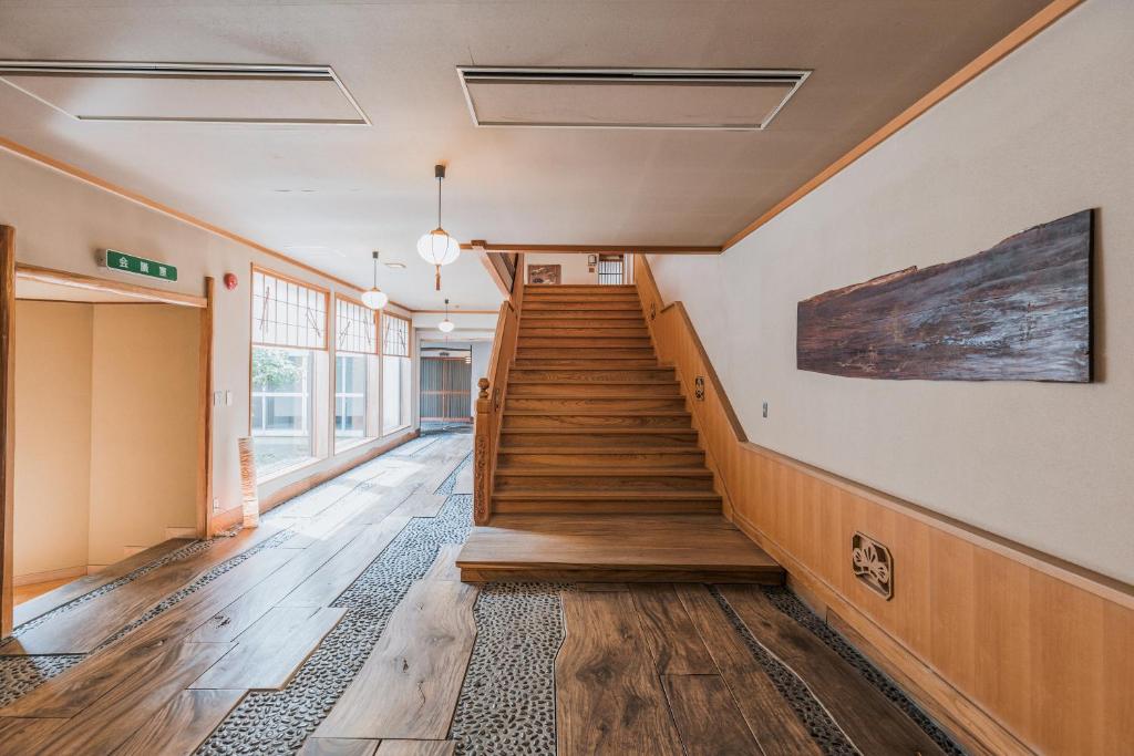 - un couloir dans un immeuble doté de parquet et d'escaliers dans l'établissement Wakamatsu Hot Spring Resort, à Hakodate
