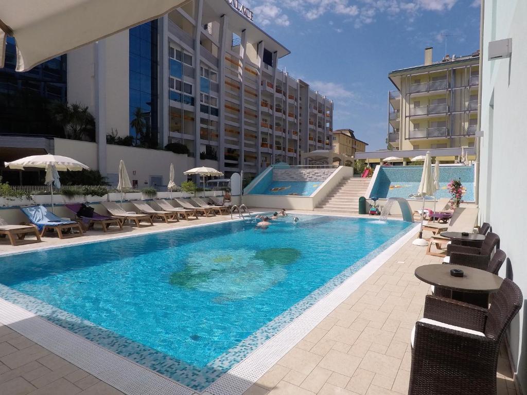 une grande piscine avec des chaises et un bâtiment dans l'établissement Hotel Ca' D'Oro Tre Stelle Superior Adults only, à Bibione