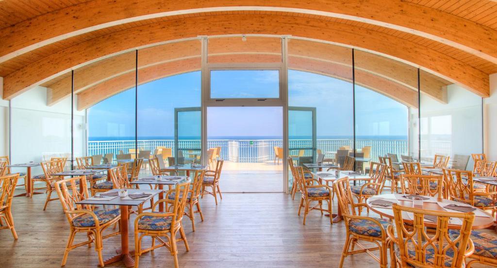 un restaurant avec des tables et des chaises et une vue sur l'océan dans l'établissement Regent's Hotel, à Lido di Jesolo