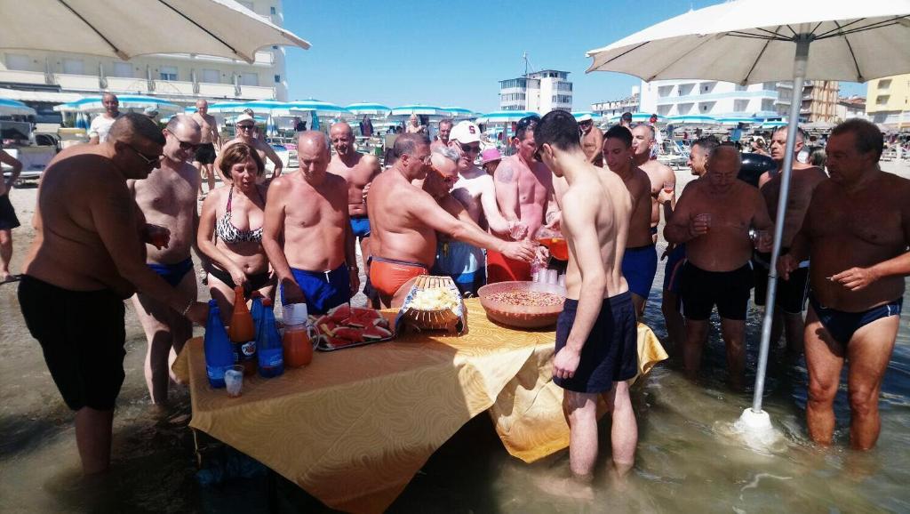 Un groupe d'hommes debout autour d'une table dans l'eau dans l'établissement Strand Hotel Colorado, à Lido di Savio