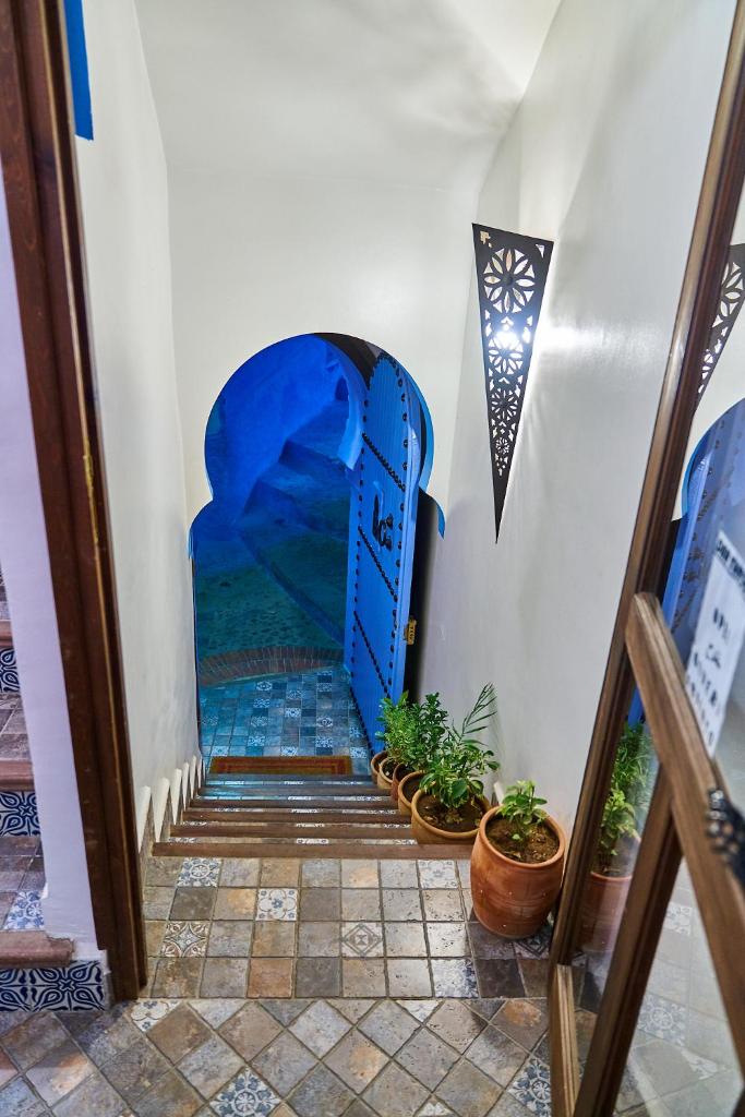 un escalier avec une porte bleue et des plantes en pot dans l'établissement Dar Yakout, à Chefchaouen