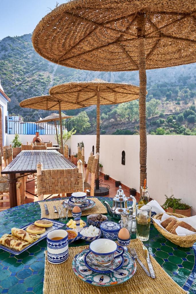 une table avec des assiettes de nourriture sur une table sous un parapluie dans l'établissement Dar Yakout, à Chefchaouen