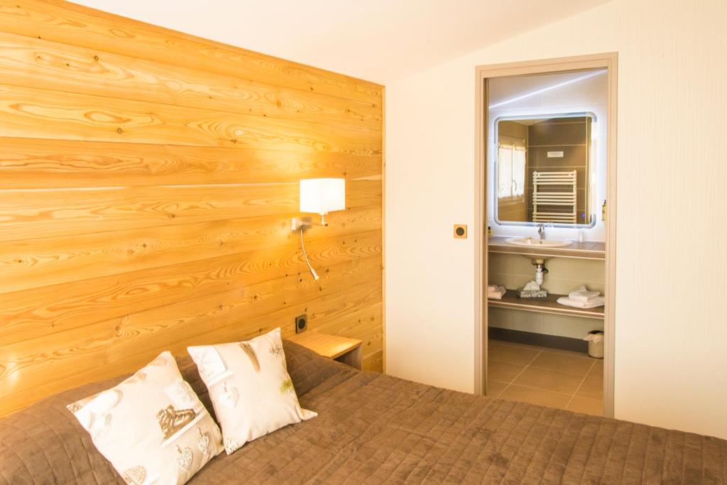 - une chambre avec un lit et un mur en bois dans l'établissement Logis Le Vernay, à Autrans