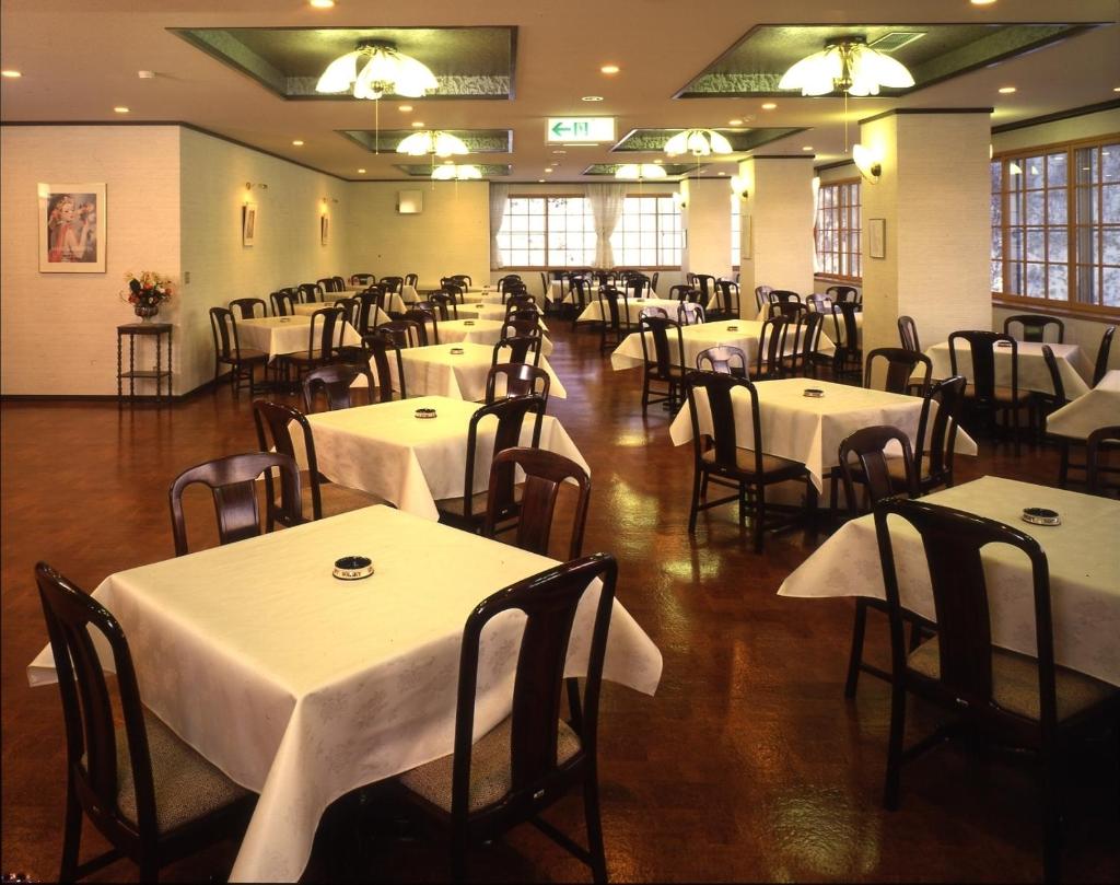 - une salle à manger avec des tables, des chaises et du linge de maison blanc dans l'établissement Kidoike Onsen Hotel, à Yamanouchi