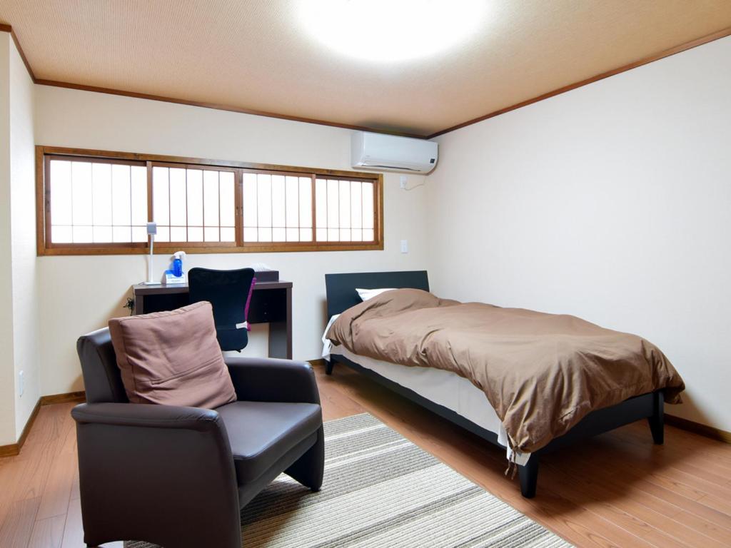 une chambre avec un lit et une chaise dans l'établissement Azuma Ryokan, à Kitakata