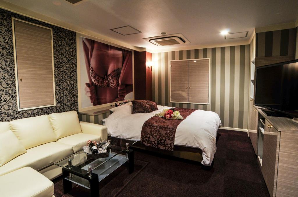 une chambre d'hôtel avec un lit et un canapé dans l'établissement Hotel Grande (Love Hotel), à Kitakyūshū