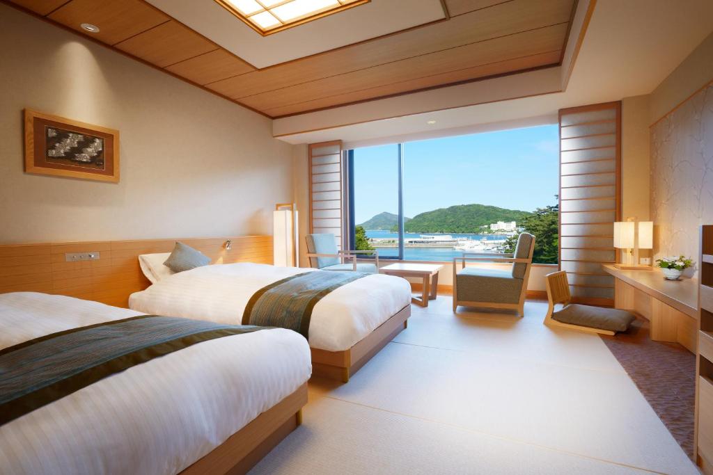 une chambre d'hôtel avec deux lits et une grande fenêtre dans l'établissement Toba International Hotel Shiojitei, à Toba
