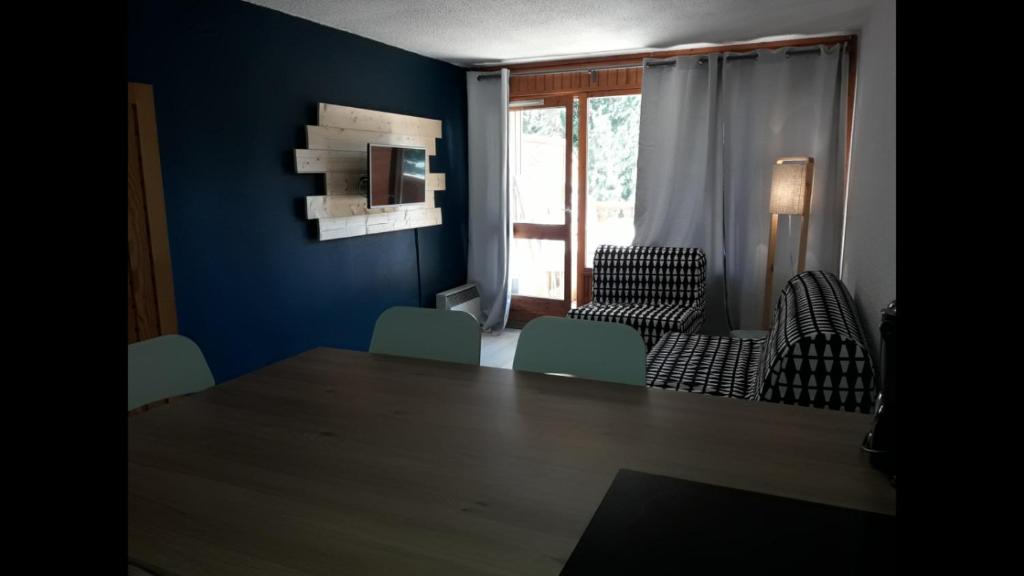 Cette chambre est dotée d'une table, de chaises et d'un mur bleu. dans l'établissement Résidence le Plein Sud, à Les Deux Alpes