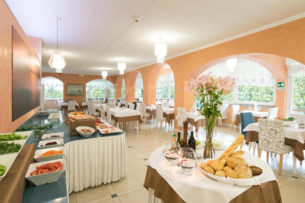 un restaurant avec des tables et des chaises avec de la nourriture dessus dans l'établissement Hotel Al Cigno, à Lignano Sabbiadoro