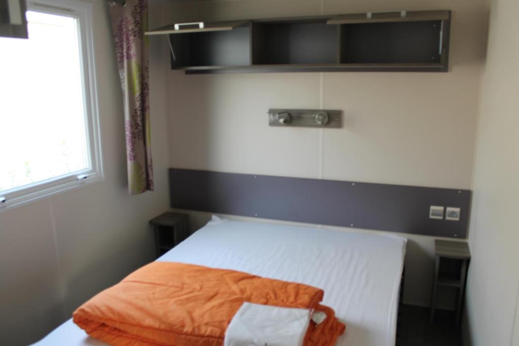 - une petite chambre avec un lit et une couverture orange dans l'établissement Camping des Roses, à Quend