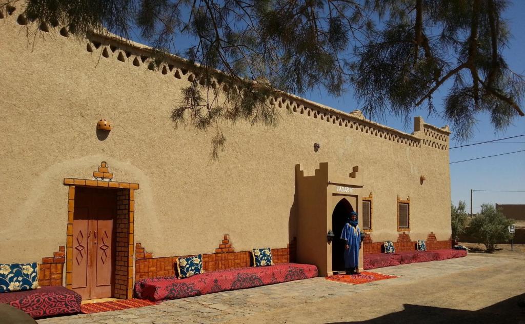 un bâtiment avec des canapés rouges sur son côté dans l'établissement Hôtel Riad Tadarte Familier, à Merzouga