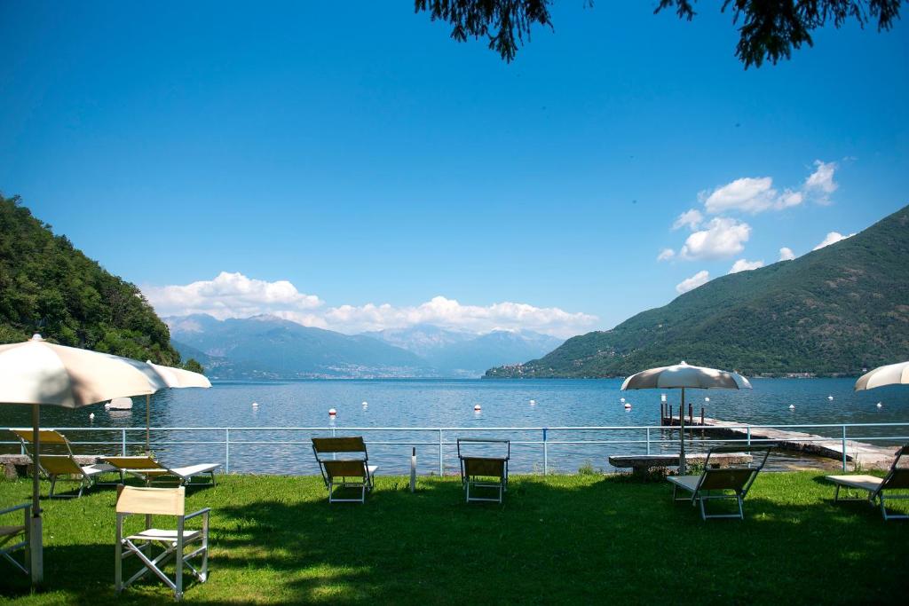 - un groupe de chaises et de parasols à côté d'un lac dans l'établissement Residence Garden, à Cannobio