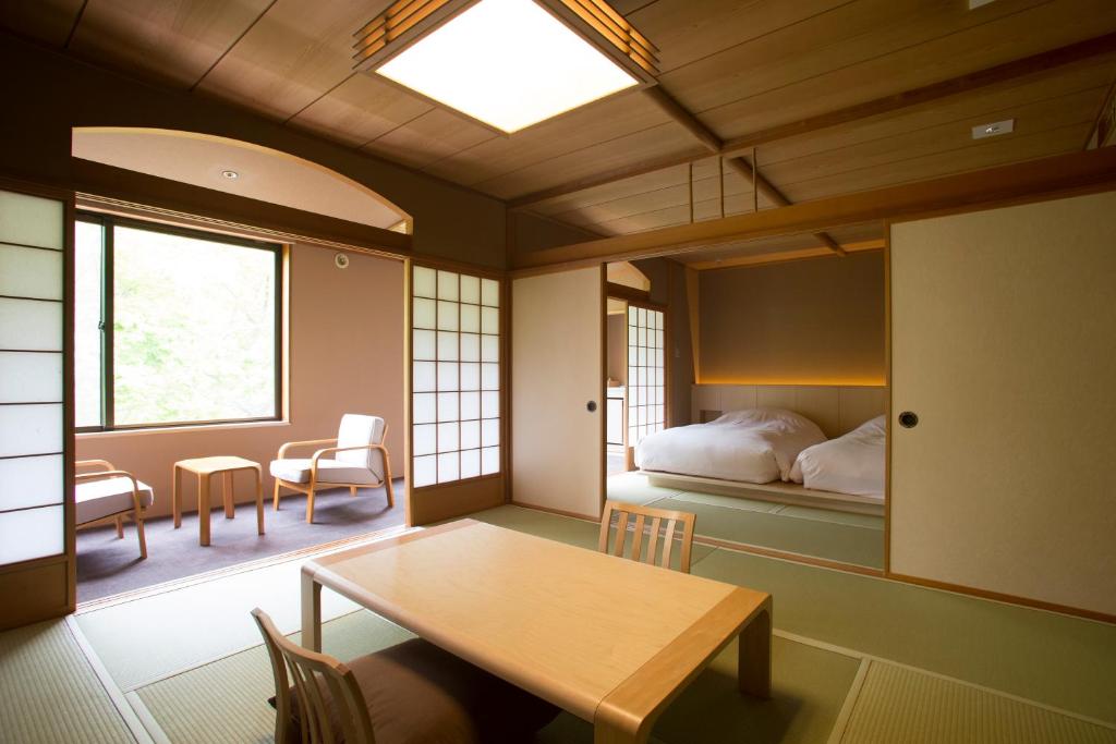une chambre avec un lit, une table et des chaises dans l'établissement Kuriya Suizan, à Jozankei