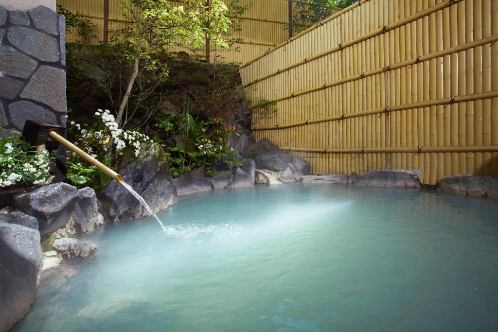 un bassin d'eau avec un tuyau d'eau dans l'établissement Unzen Iwaki Ryokan, à Unzen