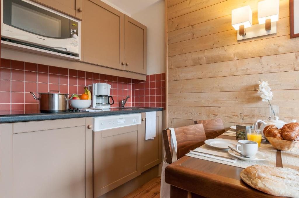 une cuisine avec une table et un comptoir dans l'établissement Résidence Pierre & Vacances Le Belmont, à Arc 1800 44 autres photos