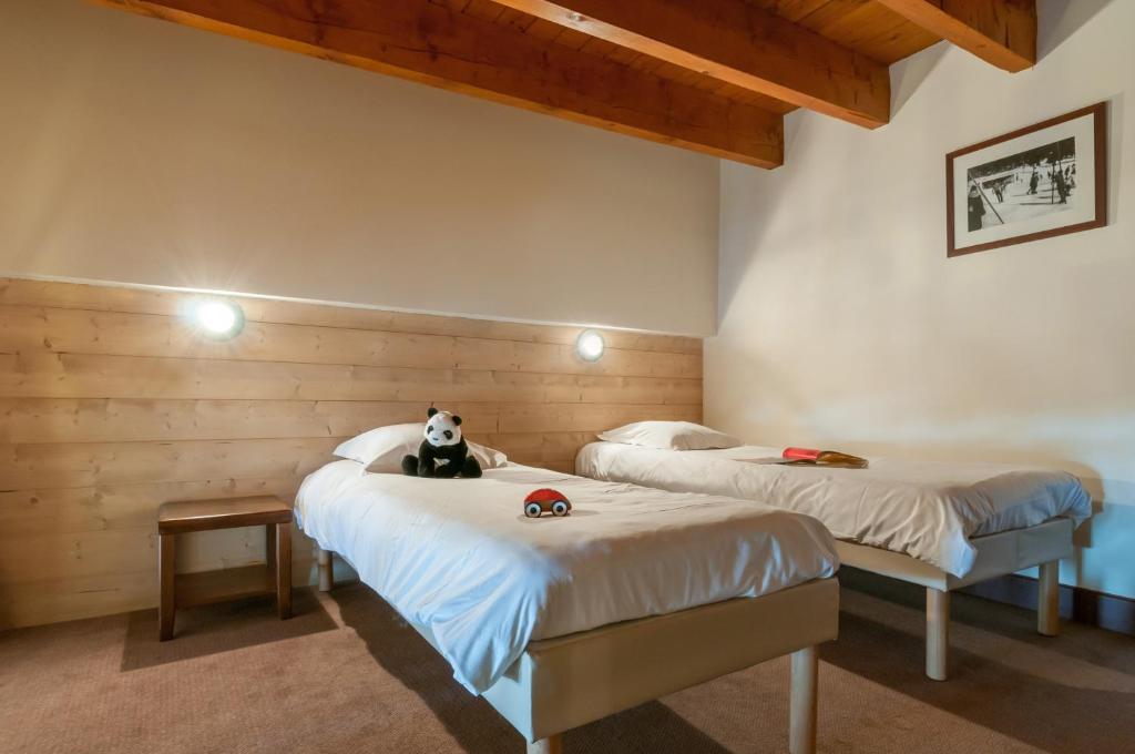 une chambre avec deux lits avec un ours en peluche assis sur eux dans l'établissement Résidence Pierre & Vacances Le Belmont, à Arc 1800