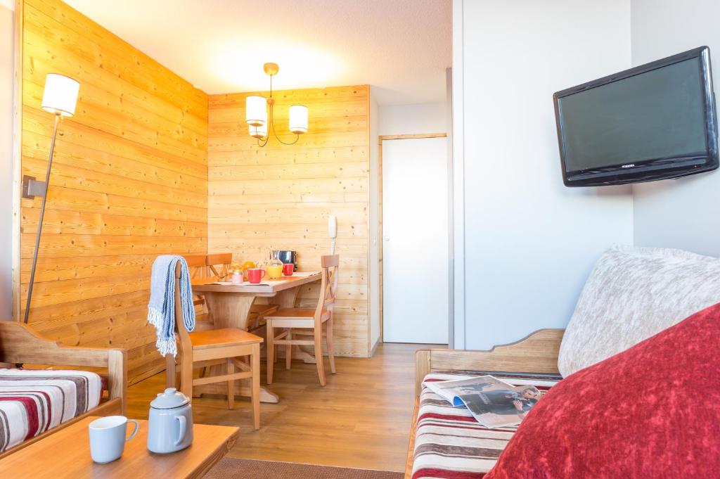 un salon avec une table à manger et une télévision dans l'établissement Résidence Pierre & Vacances Les Constellations, à Belle Plagne