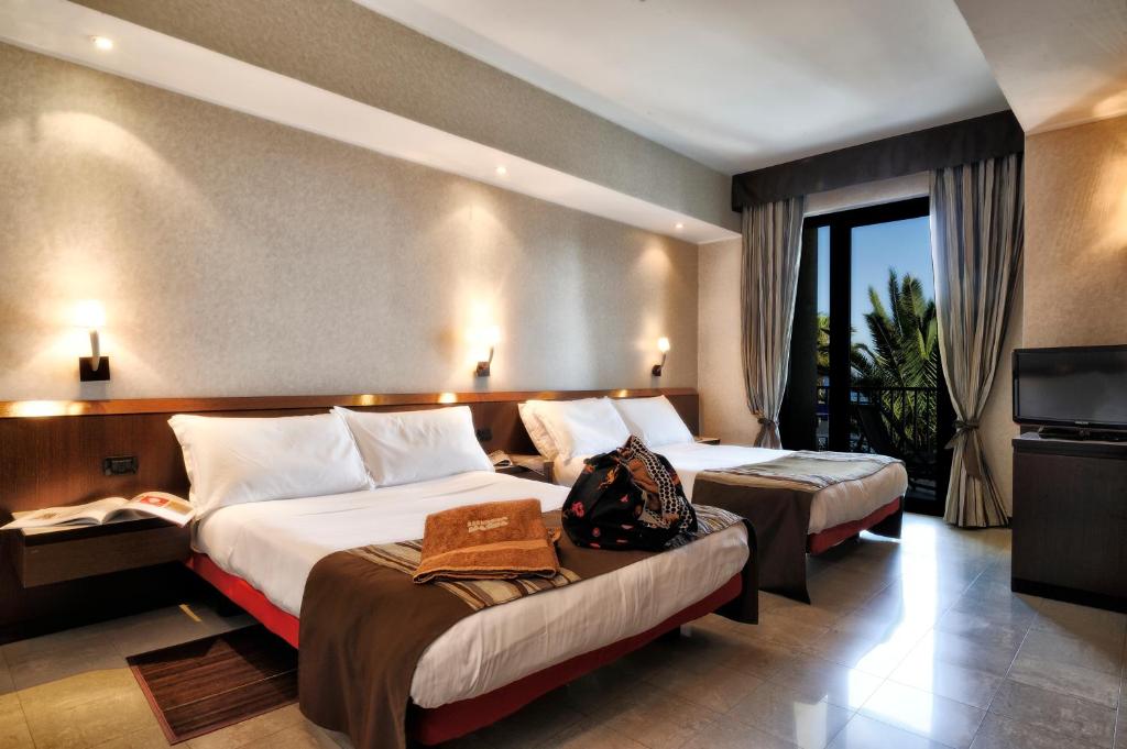 une chambre d'hôtel avec deux lits et une télévision dans l'établissement Mare Hotel, à Savone