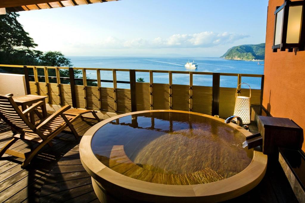 un jacuzzi sur une terrasse avec vue sur l'océan dans l'établissement Shin Kaikatei Izumi, à Izu