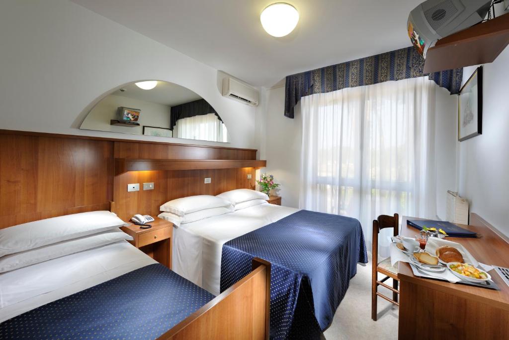 une chambre d'hôtel avec deux lits et une table avec de la nourriture dans l'établissement Hotel Vina De Mar, à Lignano Sabbiadoro