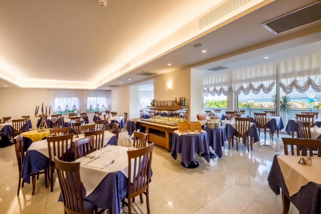 un restaurant avec des tables et des chaises dans une salle dans l'établissement Hotel Tritone, à Caorle