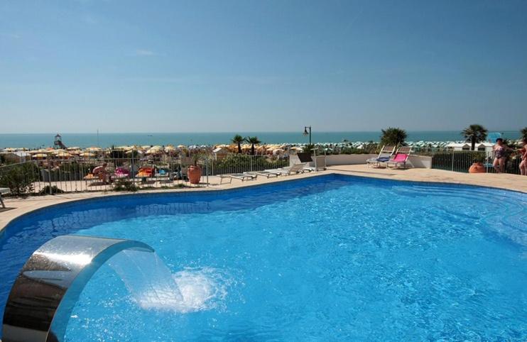 une grande piscine bleue avec vue sur la plage dans l'établissement Hotel Tritone, à Caorle