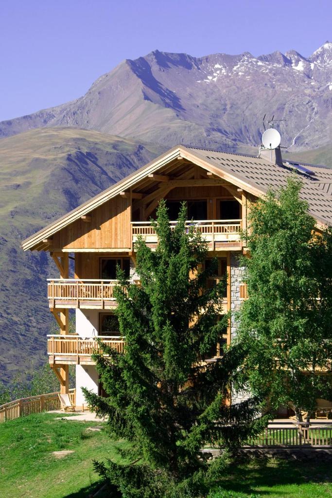 une grande maison en bois avec une montagne en arrière-plan dans l'établissement Vacanceole - Résidence Goléon -Val Ecrins, à Les Deux Alpes