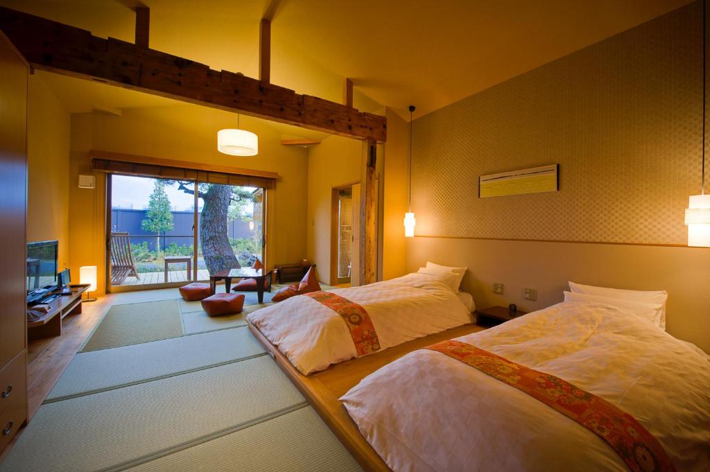 une chambre avec deux lits et une grande fenêtre dans l'établissement Migiwaya, à Yaizu