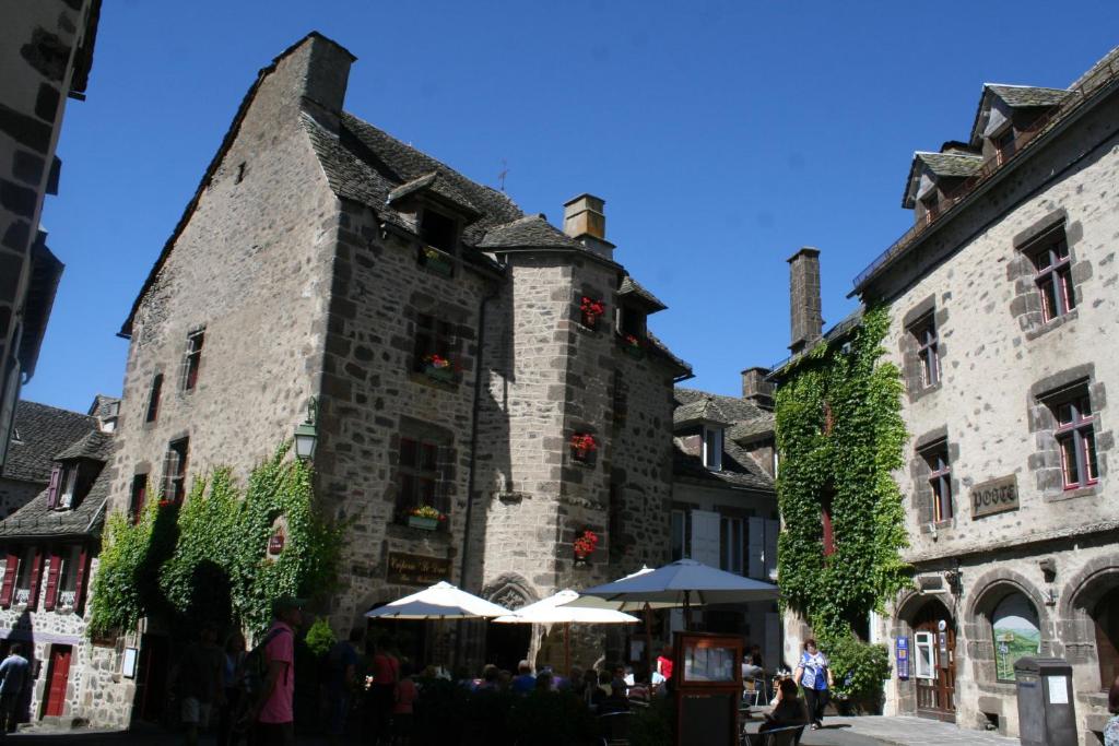 - un vieux bâtiment en pierre avec des parasols en face dans l'établissement Camping Moulin De Chaules, à Saint-Constant