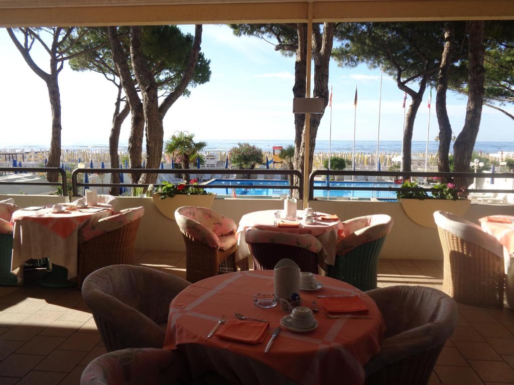 un restaurant avec des tables et des chaises et une vue sur l'océan dans l'établissement Hotel Ambasciatori Palace, à Lido di Jesolo