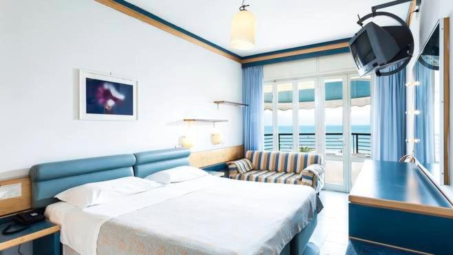 une chambre avec un lit, un canapé et une télévision dans l'établissement Hotel Ambasciatori Palace, à Lido di Jesolo