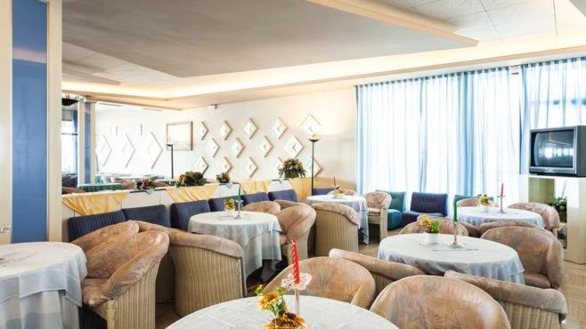 un restaurant avec des tables, des chaises et une télévision dans l'établissement Hotel Ambasciatori Palace, à Lido di Jesolo