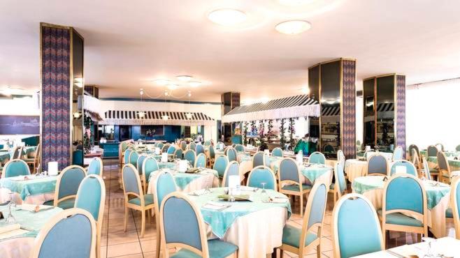 une salle à manger avec des tables bleues et des chaises blanches dans l'établissement Hotel Ambasciatori Palace, à Lido di Jesolo