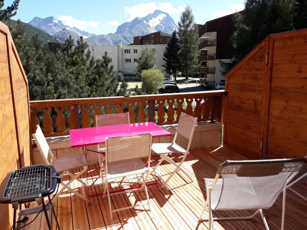 une table et des chaises roses sur une terrasse avec des montagnes dans l'établissement Résidence le Plein Sud, à Les Deux Alpes 14 autres photos