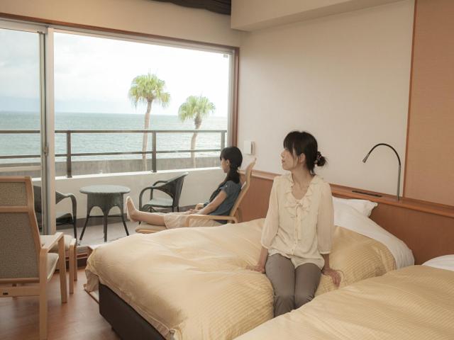 2 femmes assises sur des lits dans une chambre d'hôtel dans l'établissement Kyukamura Ibusuki, à Ibusuki