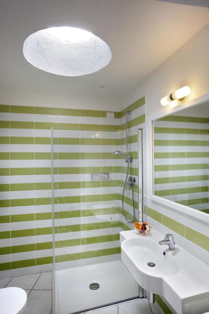 une salle de bain avec un lavabo, une douche et un miroir dans l'établissement Hotel Mare Pineta, à Santa Margherita di Pula