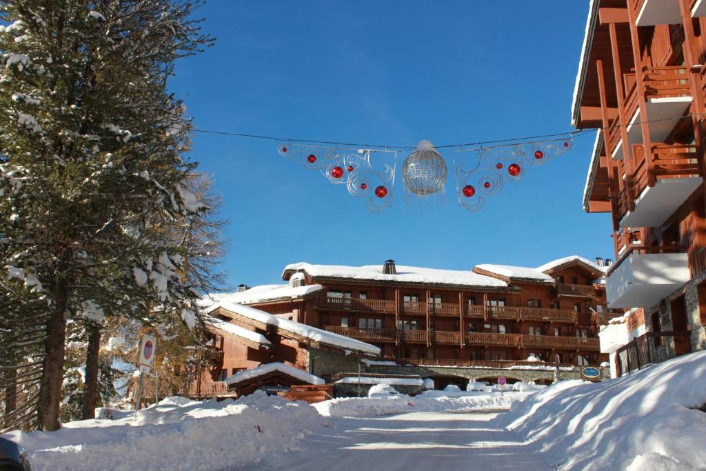 une rue enneigée avec un bâtiment en arrière-plan dans l'établissement Carene - Belle plagne - 8 personnes, à Belle Plagne