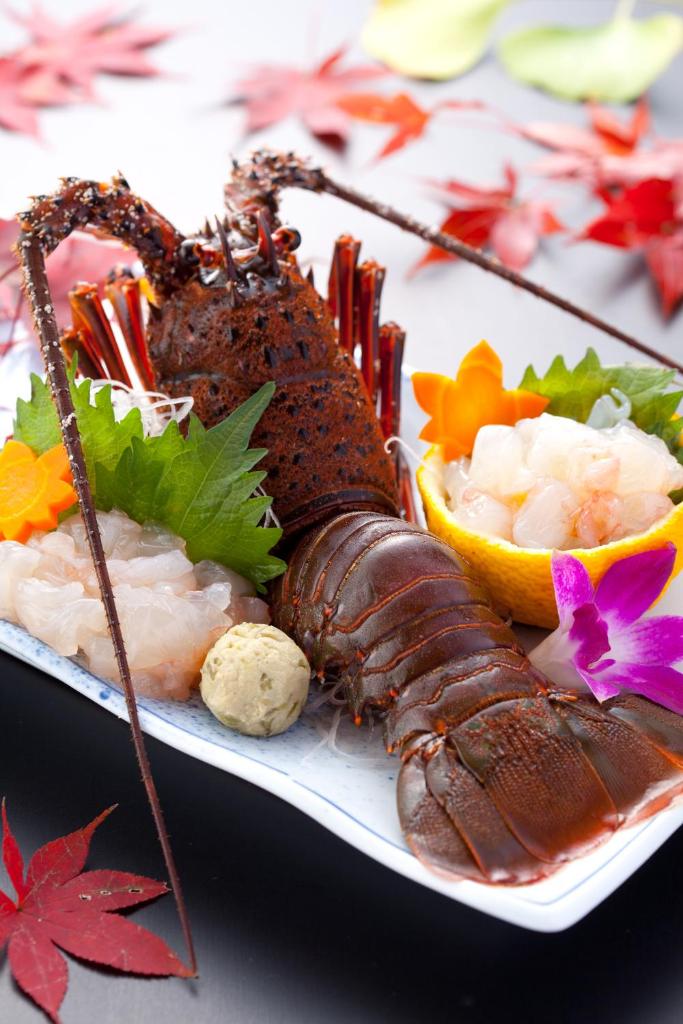 une assiette de nourriture avec du homard et d’autres denrées alimentaires dans l'établissement Hamazen Ryokan, à Hinagu