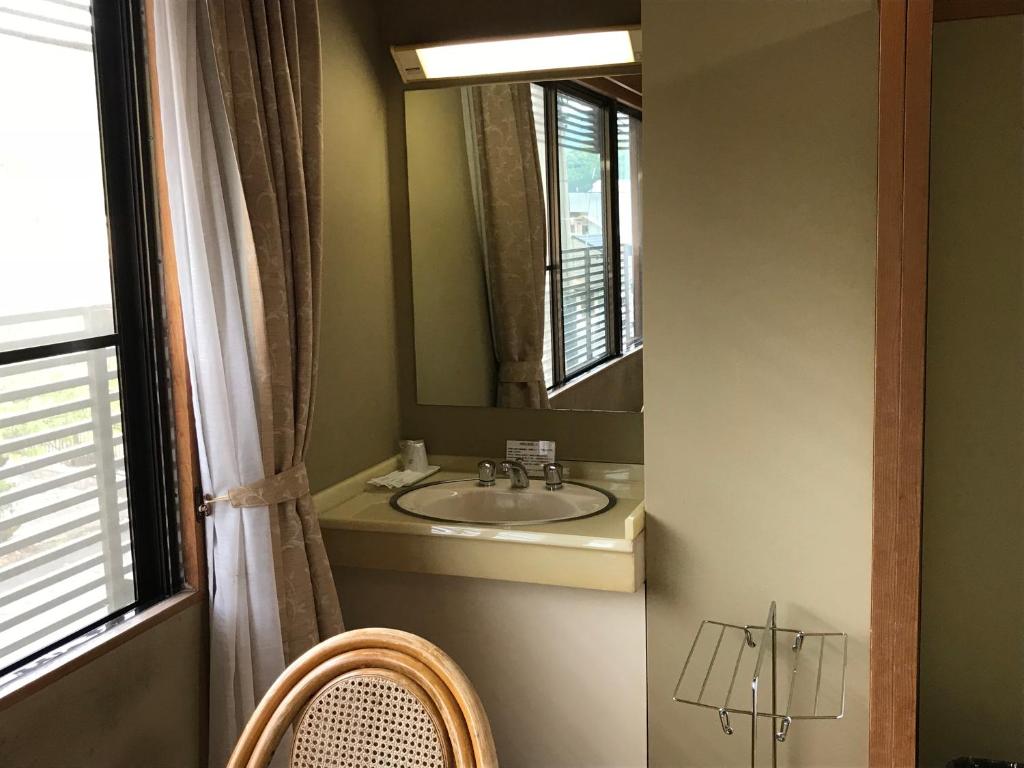 une salle de bain avec un lavabo et un miroir dans l'établissement Ryujin Onsen Marui Ryokan, à Tanabe