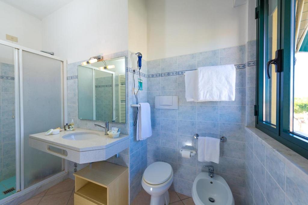 une salle de bain avec un lavabo, des toilettes et un miroir dans l'établissement Hotel Dei Tigli, à Lido di Camaiore