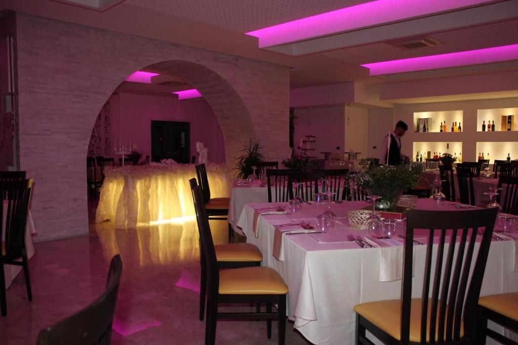 une salle à manger avec des tables et des chaises blanches et des lumières violettes dans l'établissement Hotel Miramare, à Cirò Marina